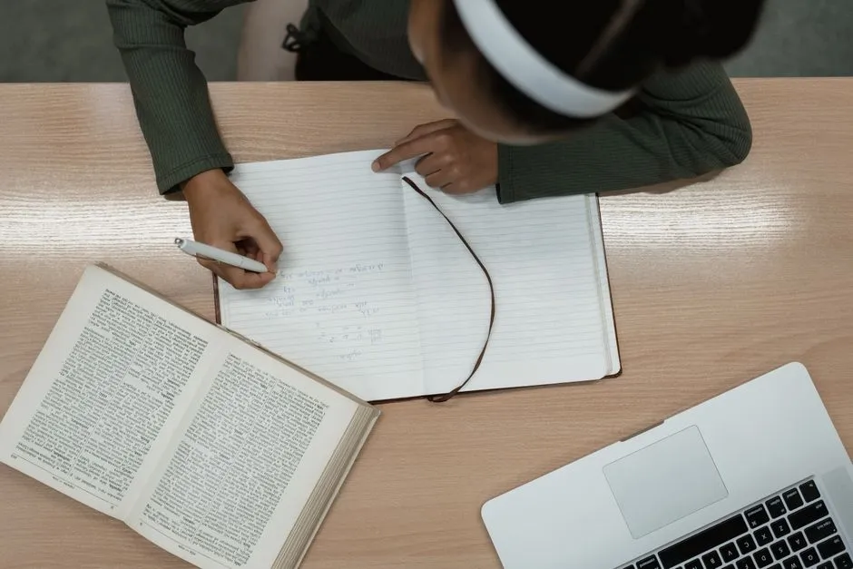 Student writing notes in a notebook while studying